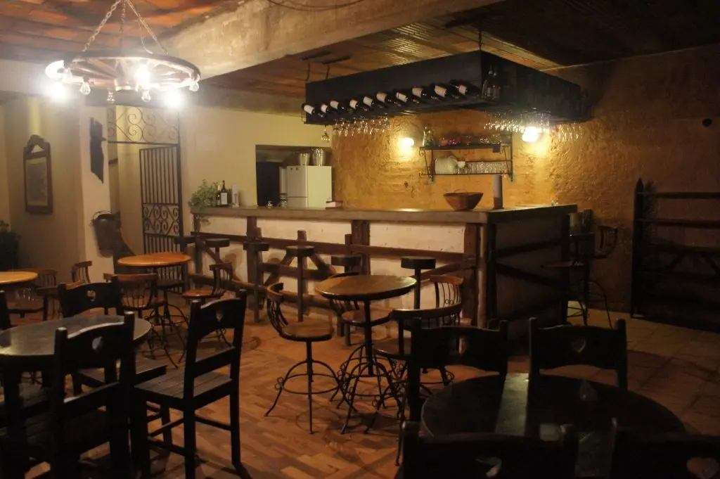 Salão do bar com balcão e mesas de madeira