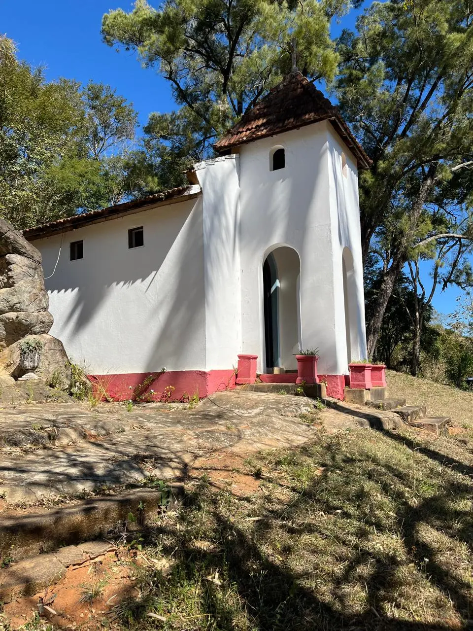 Capela branca do Jatahy cercada por árvores sob o céu azul