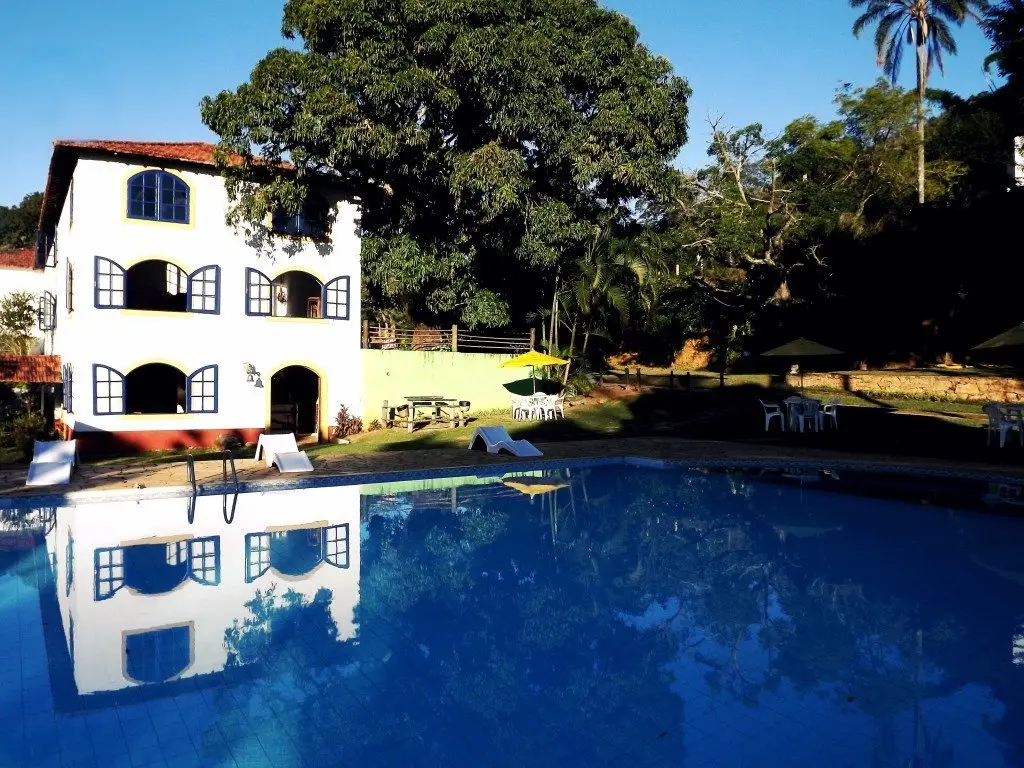 Piscina azul refletindo o casarão da Fazenda Hotel Jatahy
