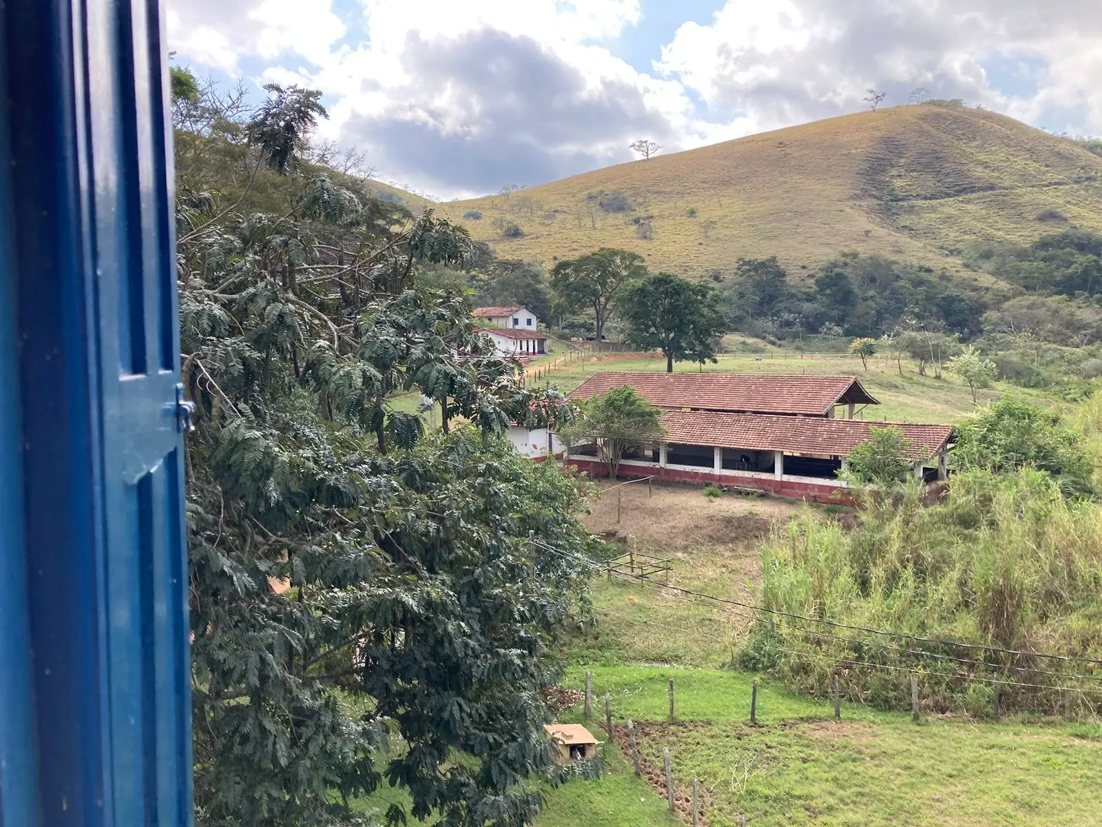 Vista da janela de um apartamento para a cocheira e os morros