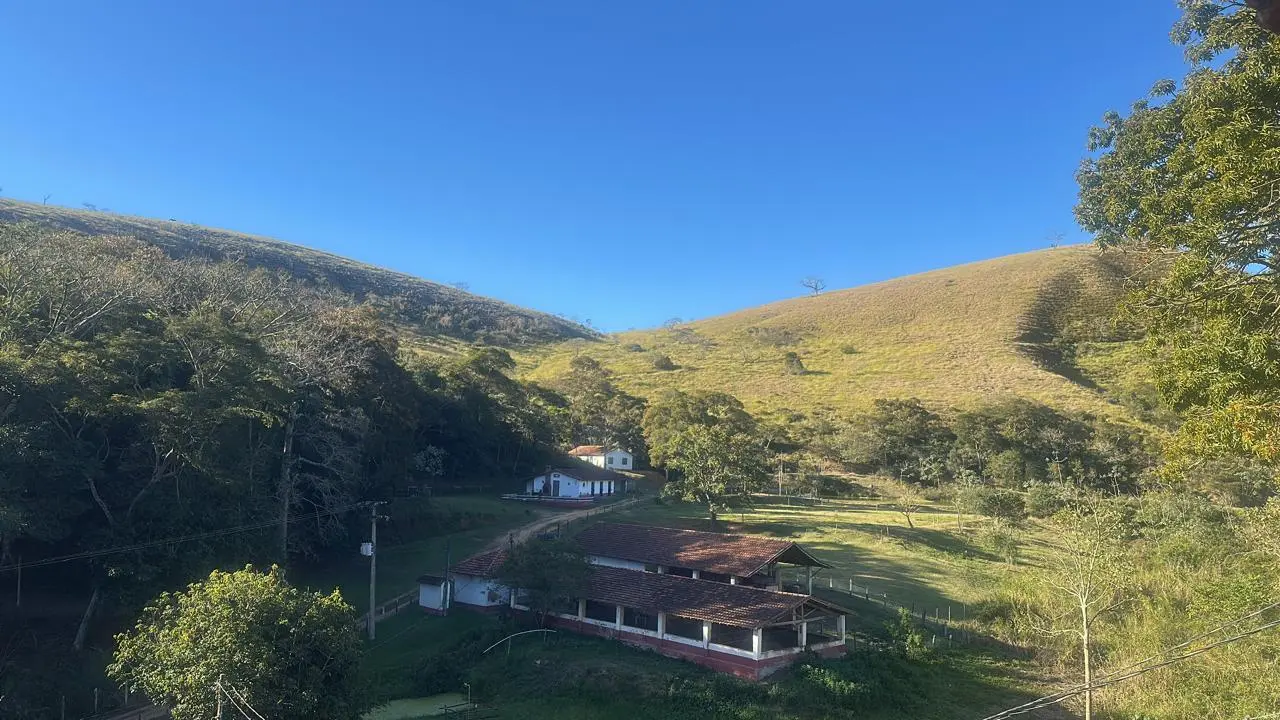 Campo, construções rurais e morros vistos de um apartamento